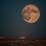 A stunning view of a moonrise from Titan's surface, showcasing Saturn's glow over the icy landscape.
