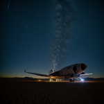 A futuristic spaceship lands in a vast desert under a starlit night sky, blending earthly landscapes with cosmic technology in a mesmerizing scene.