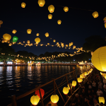 A captivating scene of countless glowing lanterns floating gracefully in the night sky during a magical lantern festival, illuminating the darkness with their warm light.