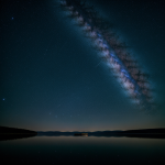 A breathtaking view of a galaxy reflected in the calm waters of a serene lake, showcasing the mesmerizing blend of celestial and earthly beauty.