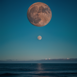 A giant moon majestically rises over the ocean horizon, casting a serene reflection on the water, creating a breathtaking celestial view.