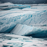A massive glacier majestically breaking into the ocean, capturing the stunning moment of natural power and beauty in a breathtaking landscape.