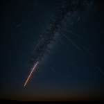 A long-exposure photograph capturing vibrant meteor streaks crossing a starry night sky, showcasing the natural beauty and wonder of cosmic events.