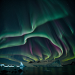 A breathtaking display of northern lights shimmering over the tranquil waters of Iceberg Bay, with vibrant colors lighting up the night sky.