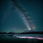 Spectacular view of polar lights illuminating the night sky over a calm mountain lake, creating a mesmerizing and colorful natural display.