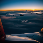 A breathtaking view of a vibrant sunset seen through an airplane window, capturing the colorful sky and peaceful clouds below.