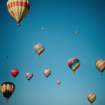 A vibrant sky filled with colorful hot air balloons, each uniquely designed, floating gracefully against a clear blue sky, creating a stunning visual display.