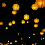 A collection of beautifully crafted paper lanterns glowing warmly against the night sky, creating a serene and magical ambiance with their soft light.