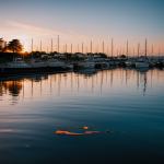 A stunning sunset over the harbor, with vibrant colors reflecting on the calm water surface, capturing the essence of natural beauty and tranquility.