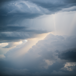 A dramatic scene of a radiant light beam piercing through dark, ominous thunderclouds, highlighting the contrast between light and shadow in nature.