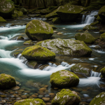 A stunning view of mossy rocks near a clear waterfall, showcasing nature's beauty with lush greenery and sparkling water creating a tranquil atmosphere.