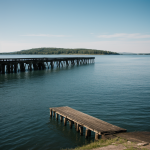 A serene view of an old pier extending into a still lake, reflecting the tranquil landscape in the calm water surface, perfect for relaxation and mindfulness.