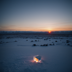 A mesmerizing sunset on a distant icy planet, with vibrant hues painting the serene, frozen landscape and ice crystals glistening under the fading light.